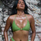 Woman wearing a green bikini standing against a rocky background