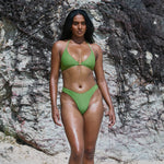 Woman in a green bikini standing against a rocky background