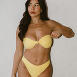 Woman wearing a yellow bikini against a plain background