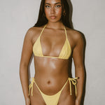 Woman wearing a yellow bikini against a plain background
